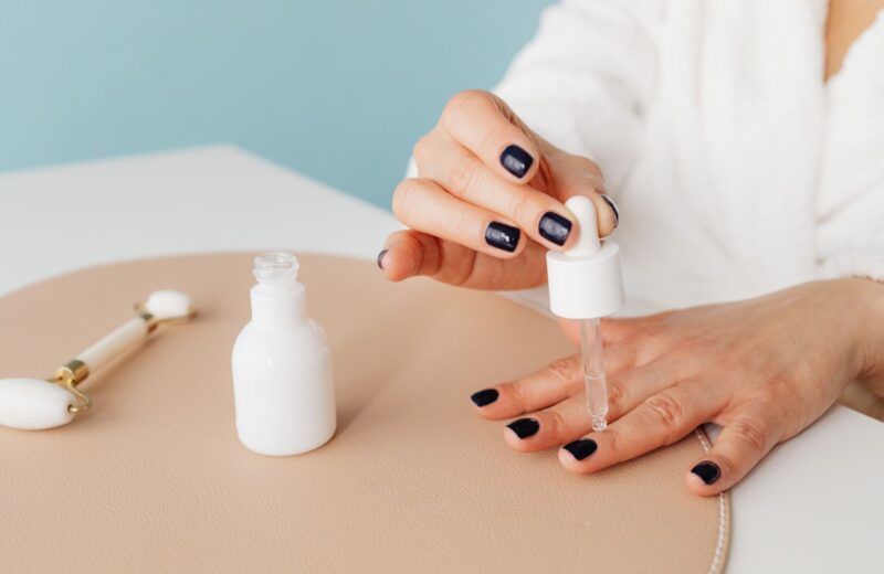 A drop of cuticle oil applied to dark painted nails
