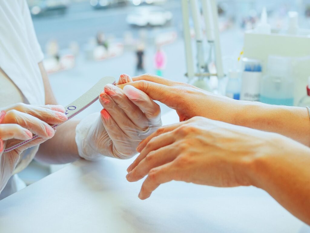 A technician filing a client's nail into shape