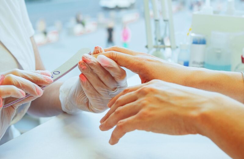 A technician filing a client's nail into shape