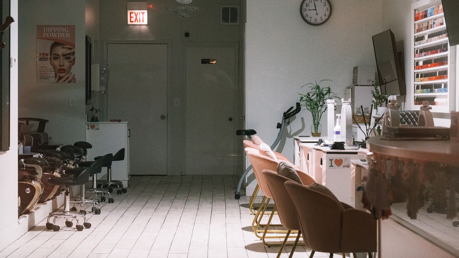 Manicure desks and chairs in a bright nail studio with a polish shelf