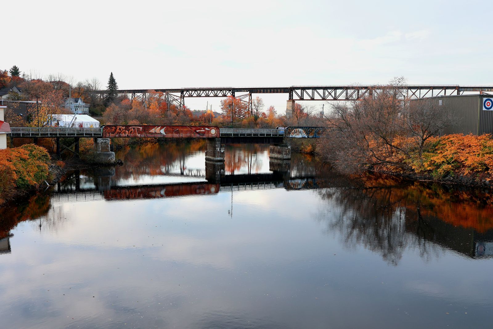 Two bridges over a calm river in autumn, the town on the far bank