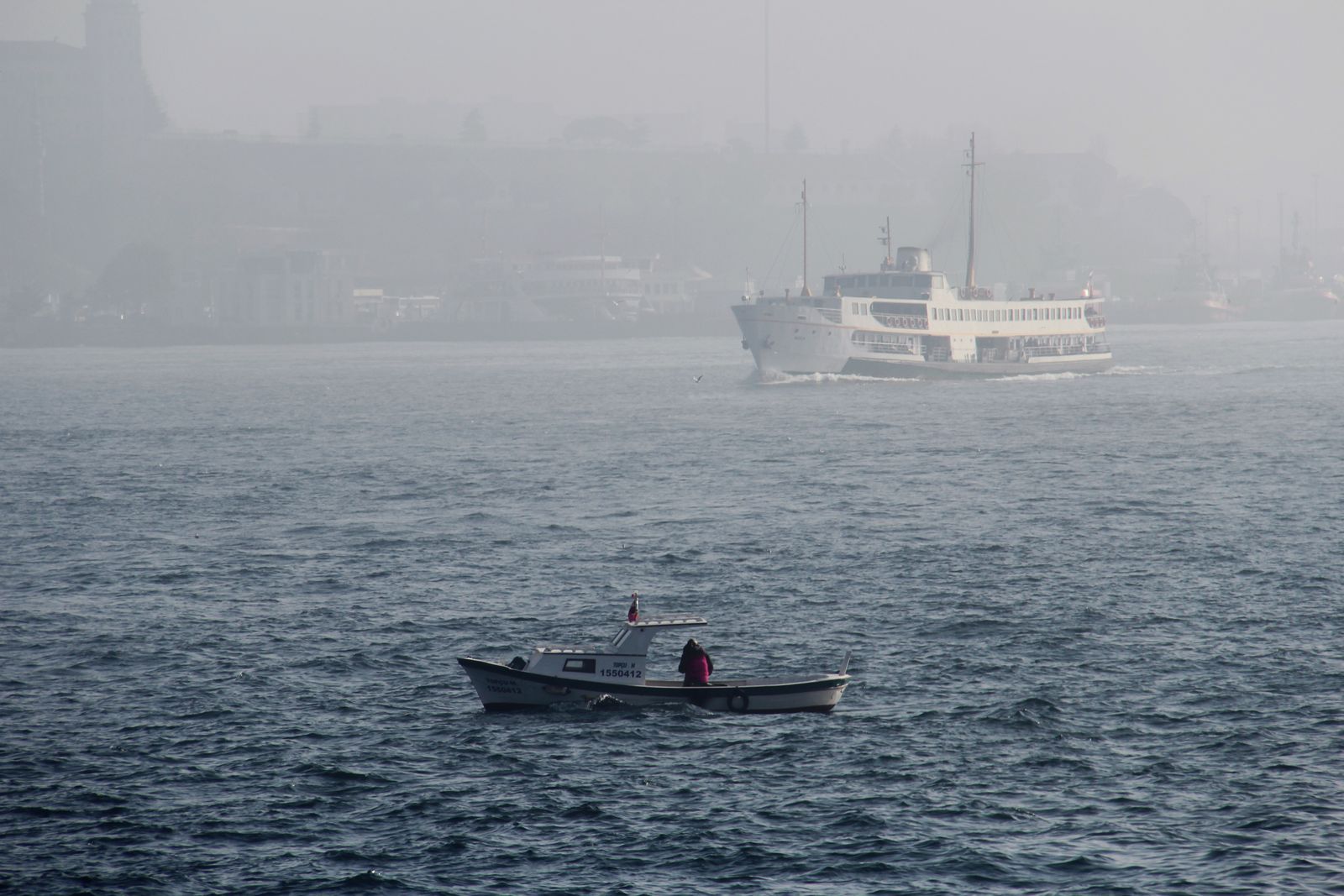 Two boats crossing a grey sea in thick fog