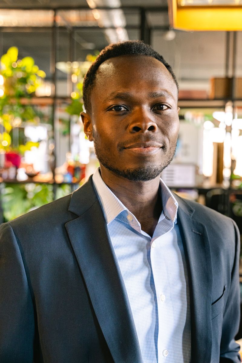 Portrait of a man in a dark blazer and open-collar shirt in an office with plants