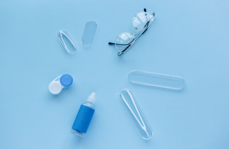 Contact lens case, solution and glasses on a blue background
