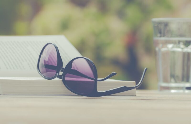 Sunglasses resting on an open book outdoors
