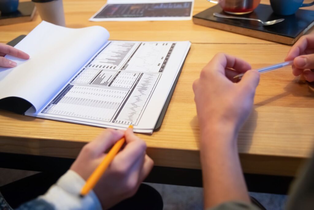 Hands with a pencil over a printed plan on a meeting table