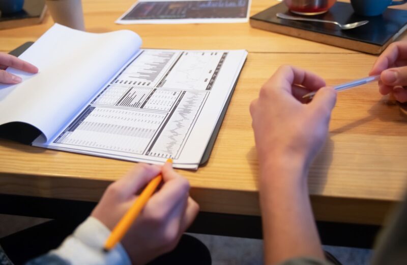 Hands with a pencil over a printed plan on a meeting table