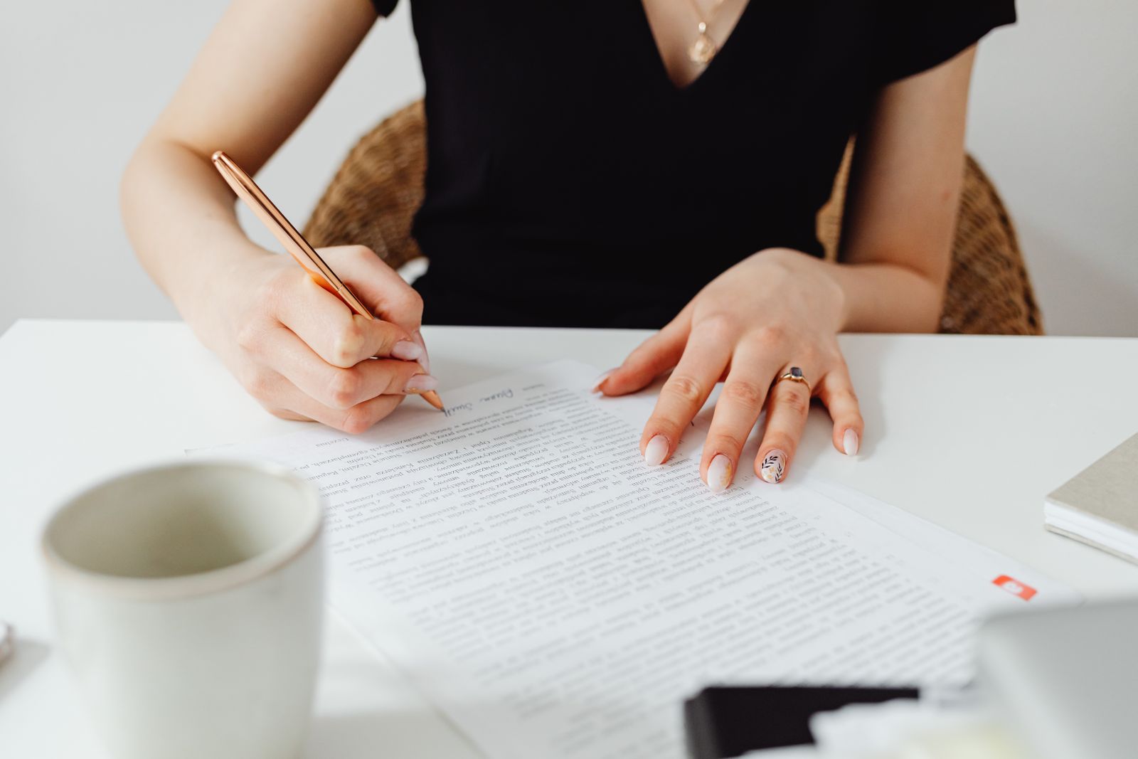 A writer editing a printed page with a pen beside a cup of coffee