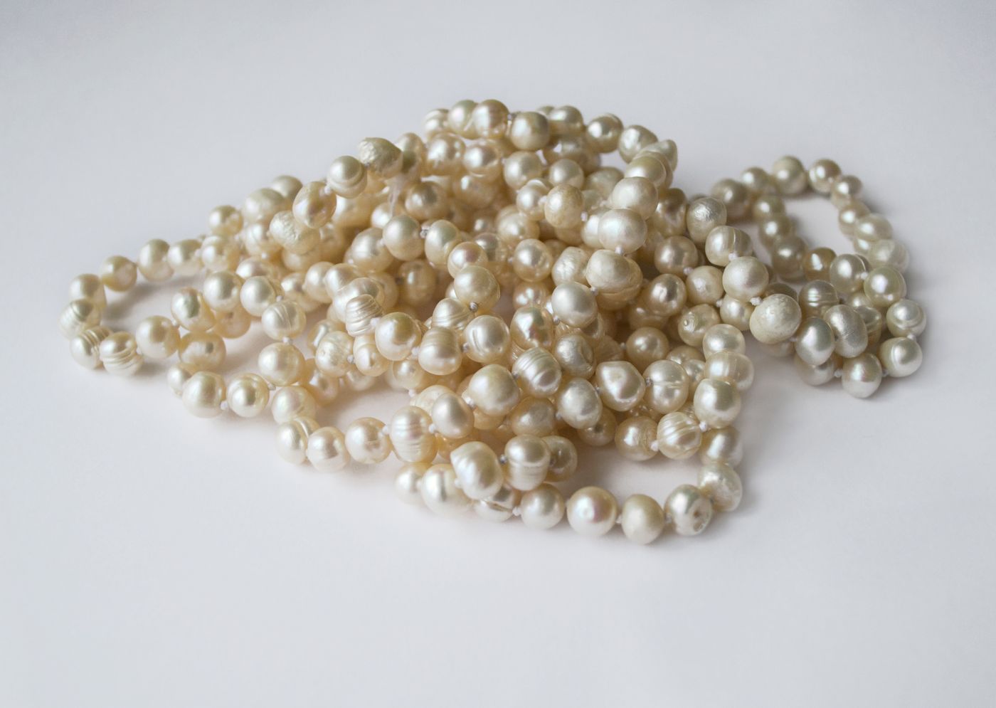 Loose freshwater pearl strands piled on a white surface