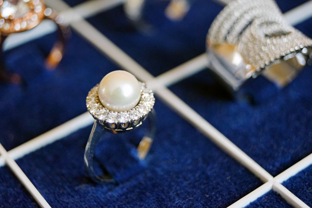 A pearl ring with a ring of small diamonds in a navy velvet display tray
