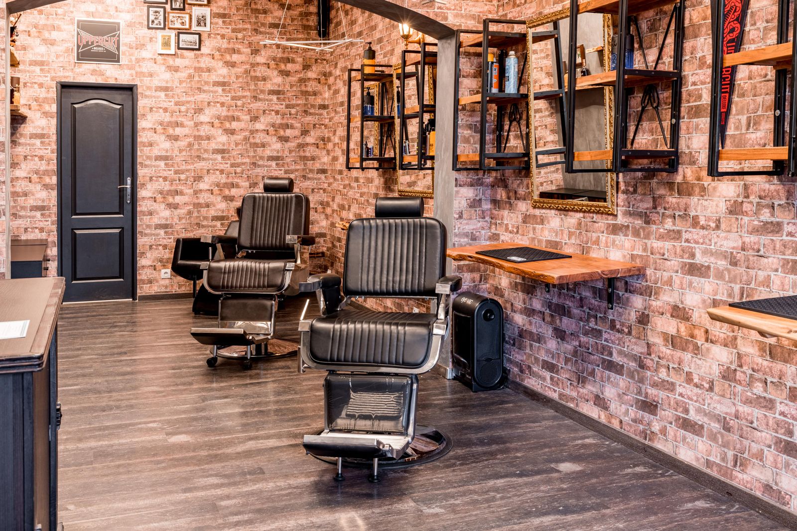 Barber chairs and mirrors along a brick wall in an empty shop