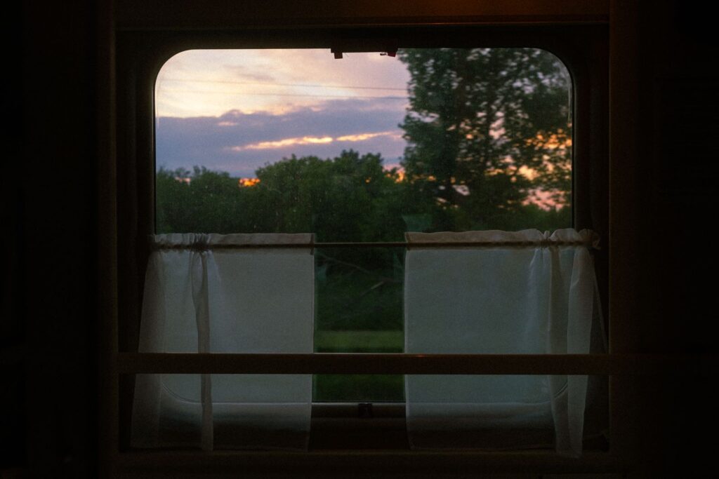 The view of fields at sunset through an old train window