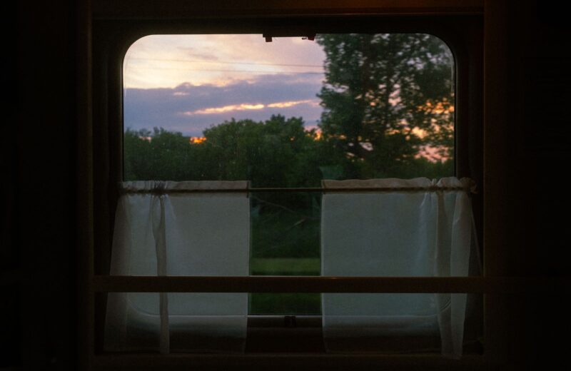 The view of fields at sunset through an old train window