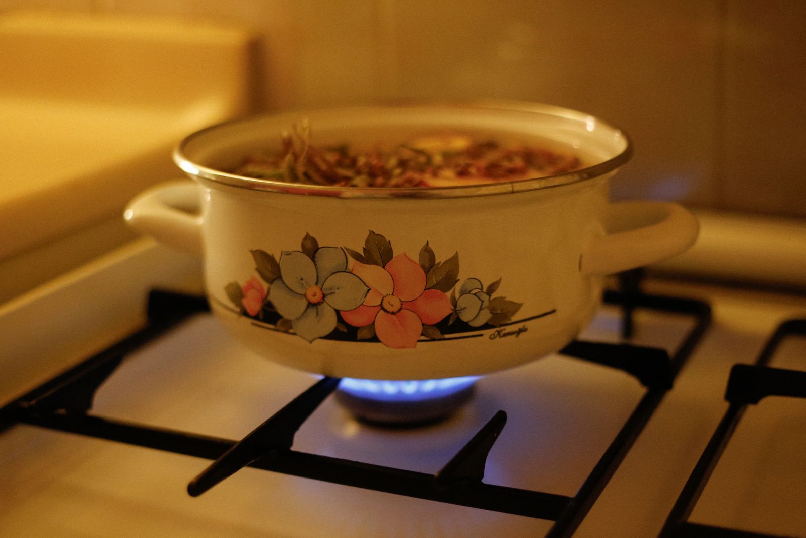 An enamel pot of soup simmering on a gas ring