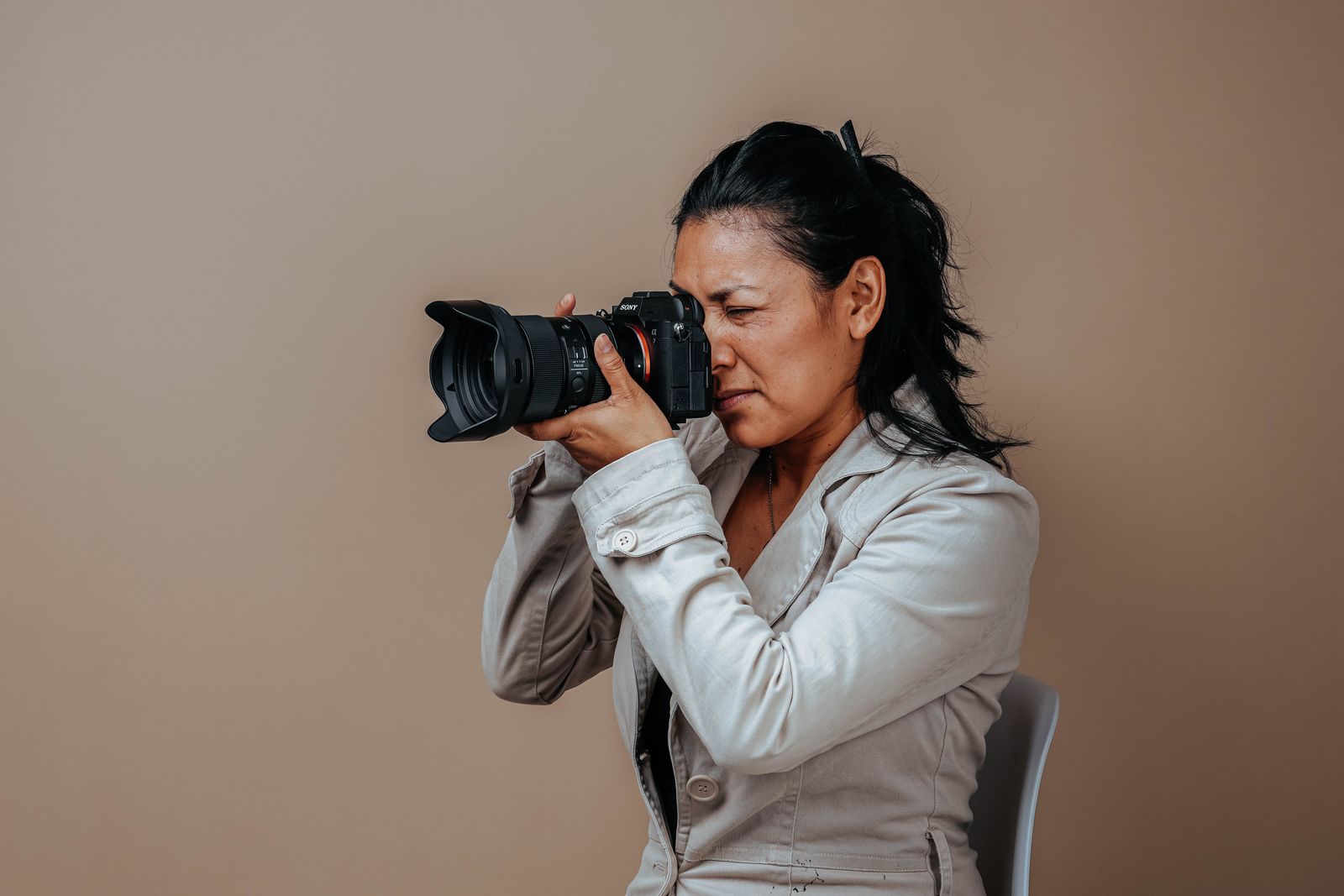 A photographer in a light jacket looking through her camera