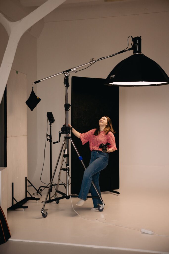 A photographer adjusting a large light on a boom arm in a studio