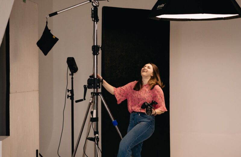 A photographer adjusting a large light on a boom arm in a studio
