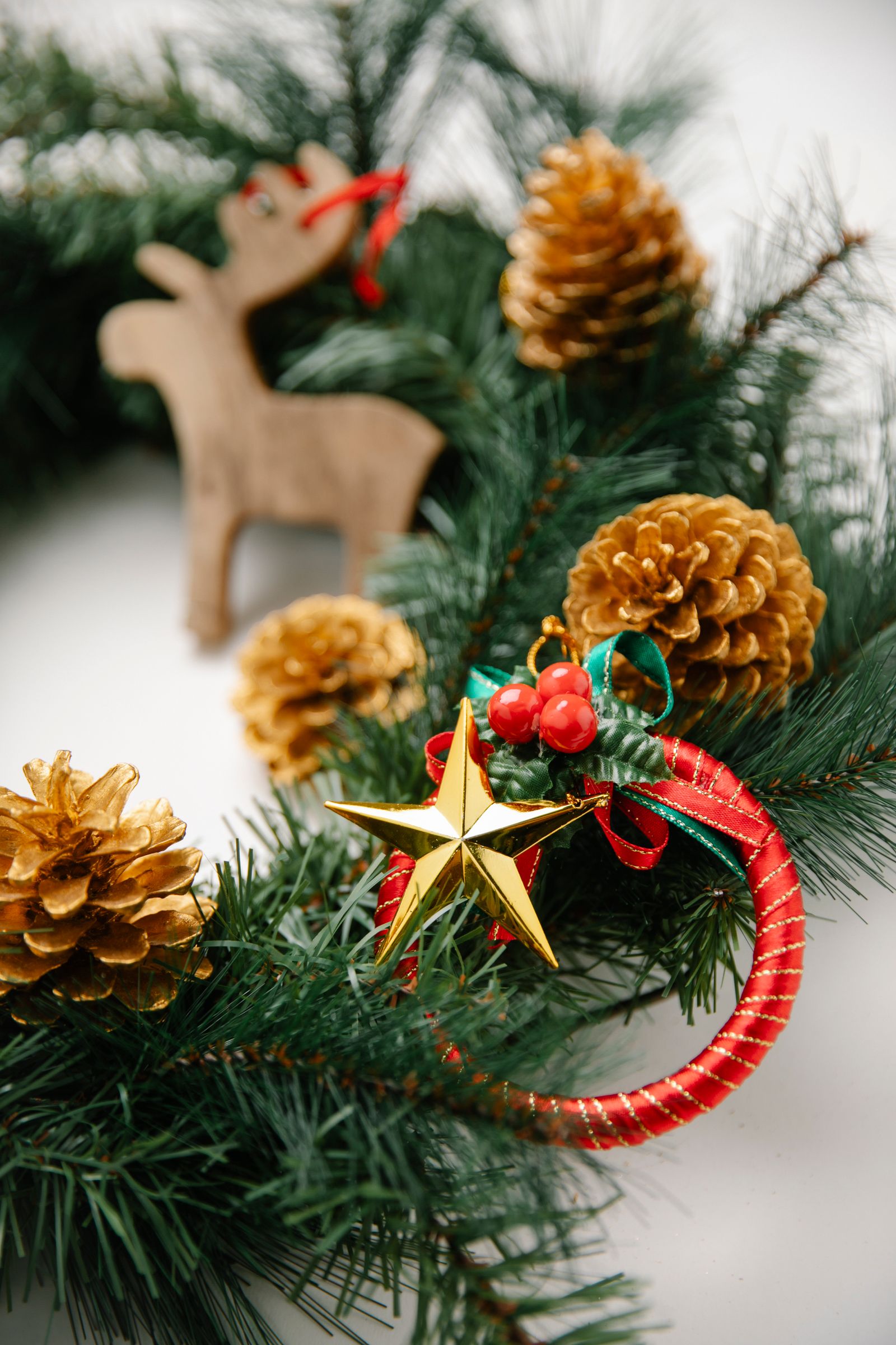 A pine garland with cones and a wooden star laid on a white table