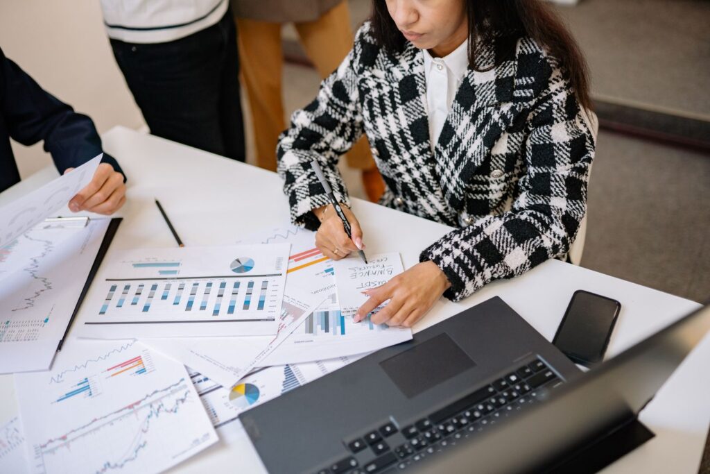 A woman reviewing printed charts beside a laptop at a meeting table