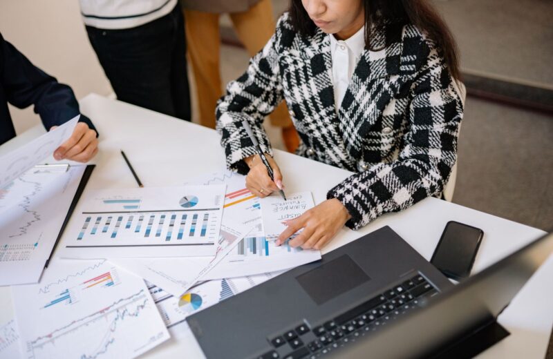 A woman reviewing printed charts beside a laptop at a meeting table