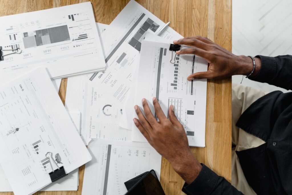 Top view of a person reviewing documents spread on a wooden desk