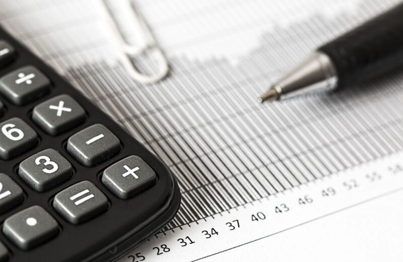 A calculator and a pen resting on a printed bar chart