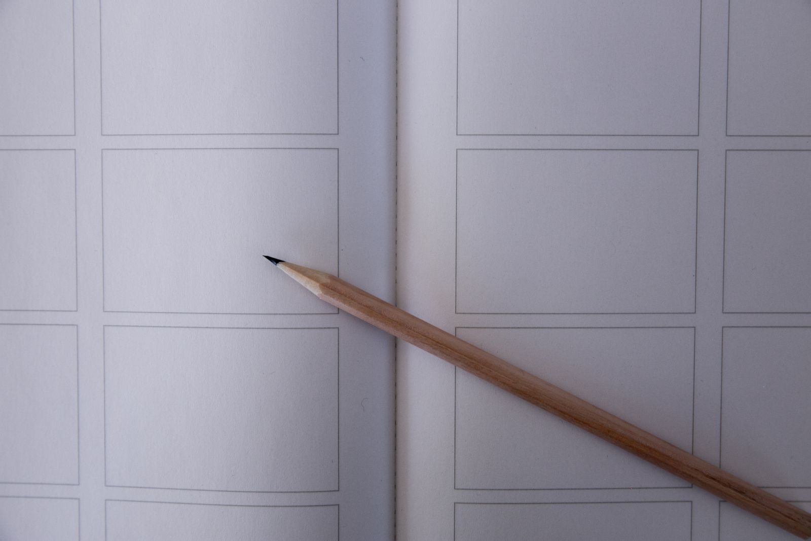 A pencil resting on a blank storyboard sheet with empty frames