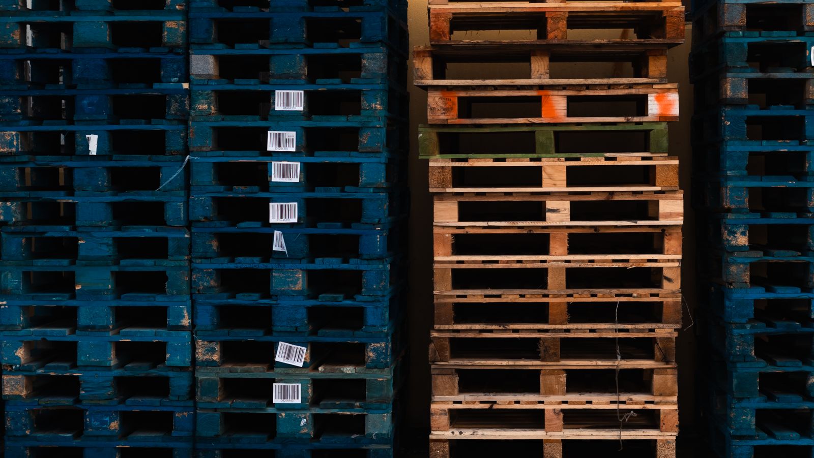 Stacks of wooden pallets with barcode labels in a warehouse