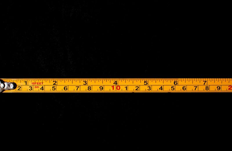 A yellow tape measure stretched out on a black surface