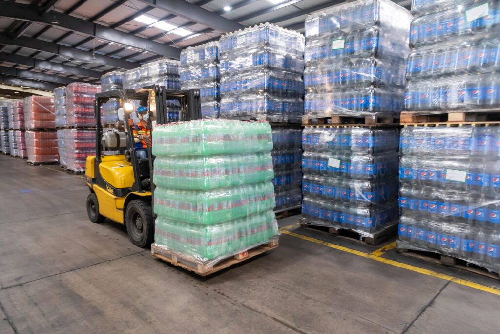 A forklift carrying a pallet of wrapped goods through a warehouse