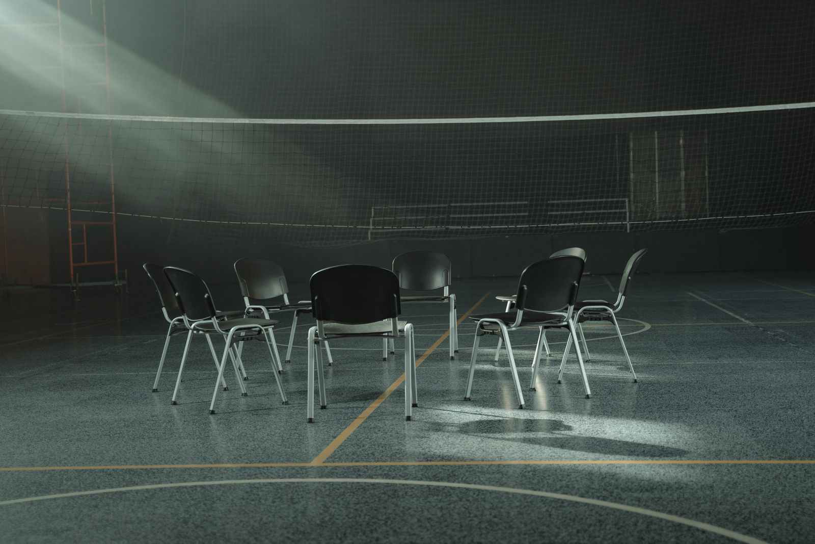 Empty chairs set out in a circle in a sunlit hall