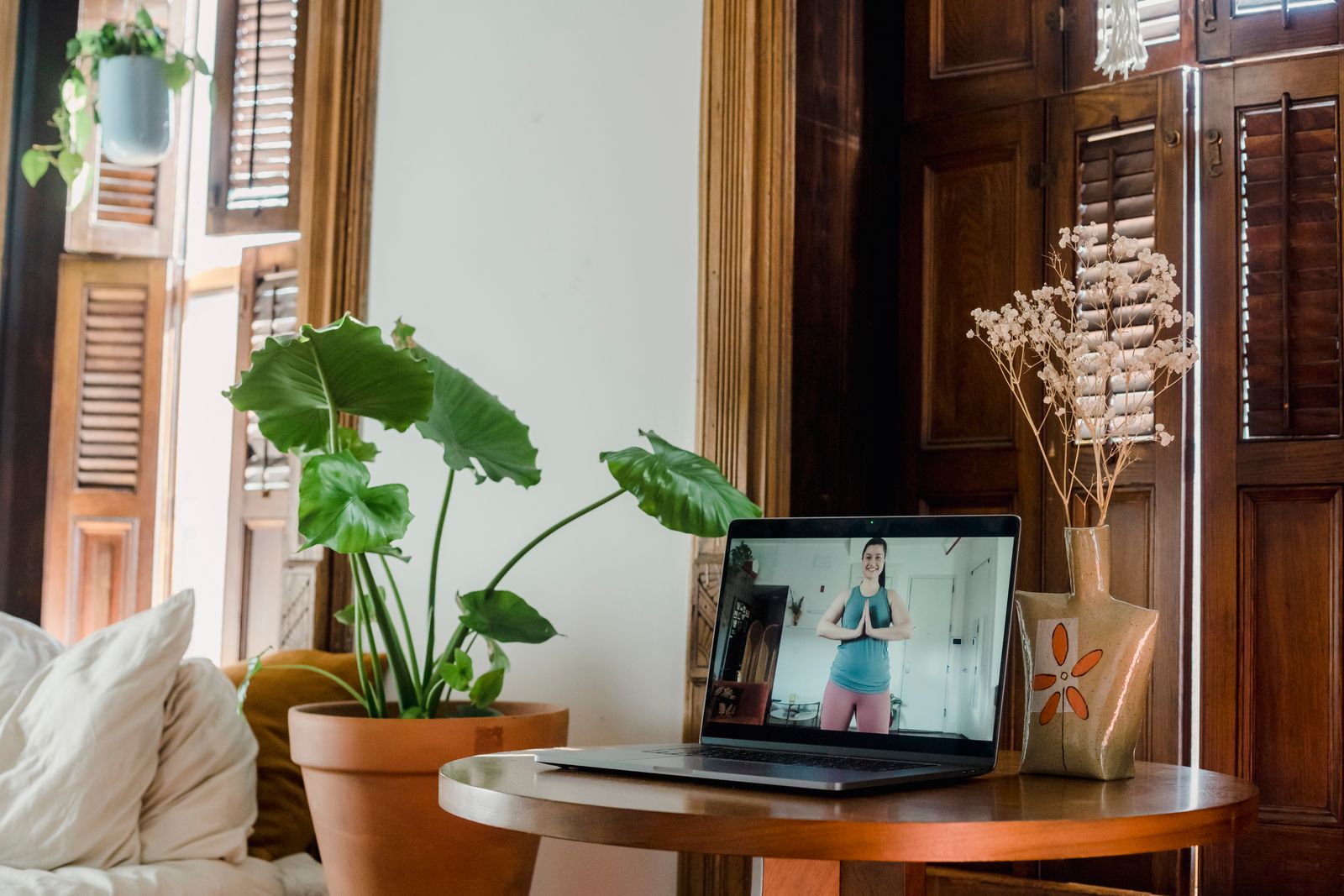 A laptop on a round table beside house plants, set up for a video session