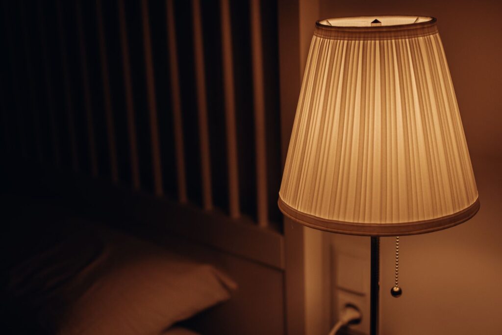 A bedside lamp glowing in a dark bedroom