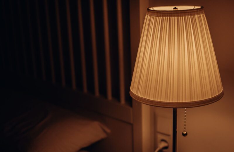 A bedside lamp glowing in a dark bedroom