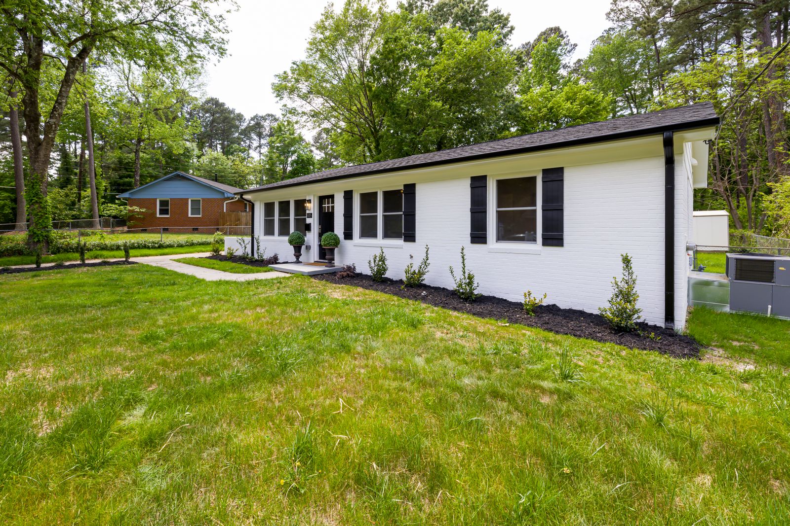 Single-storey white house with dark shutters on a wide green lawn