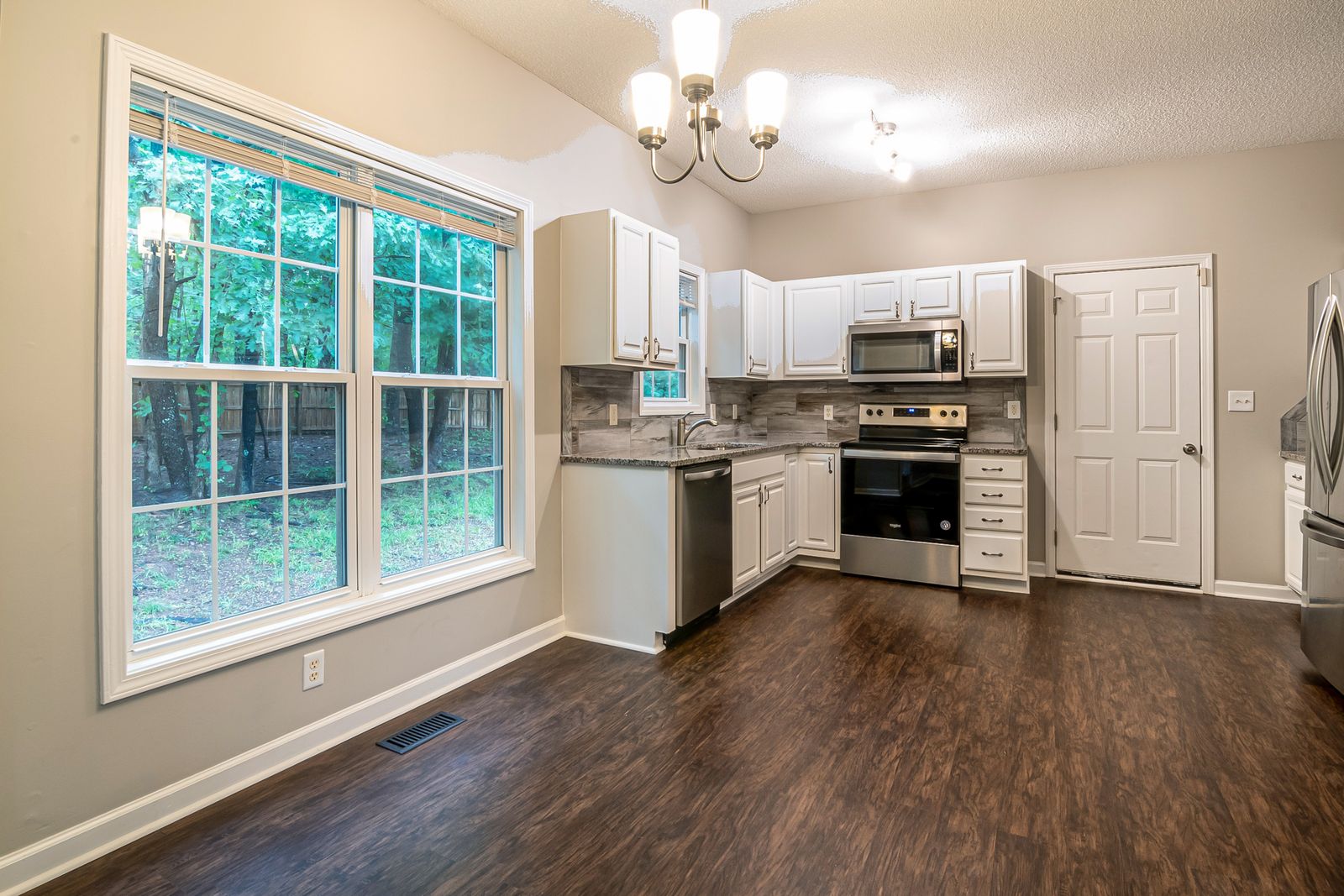 Kitchen with white cabinets, a large window and a wooden floor