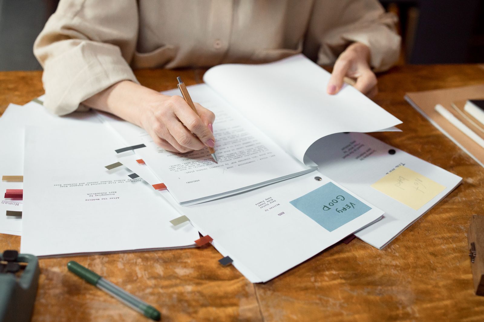 Hands sorting through papers and plans on a wooden desk