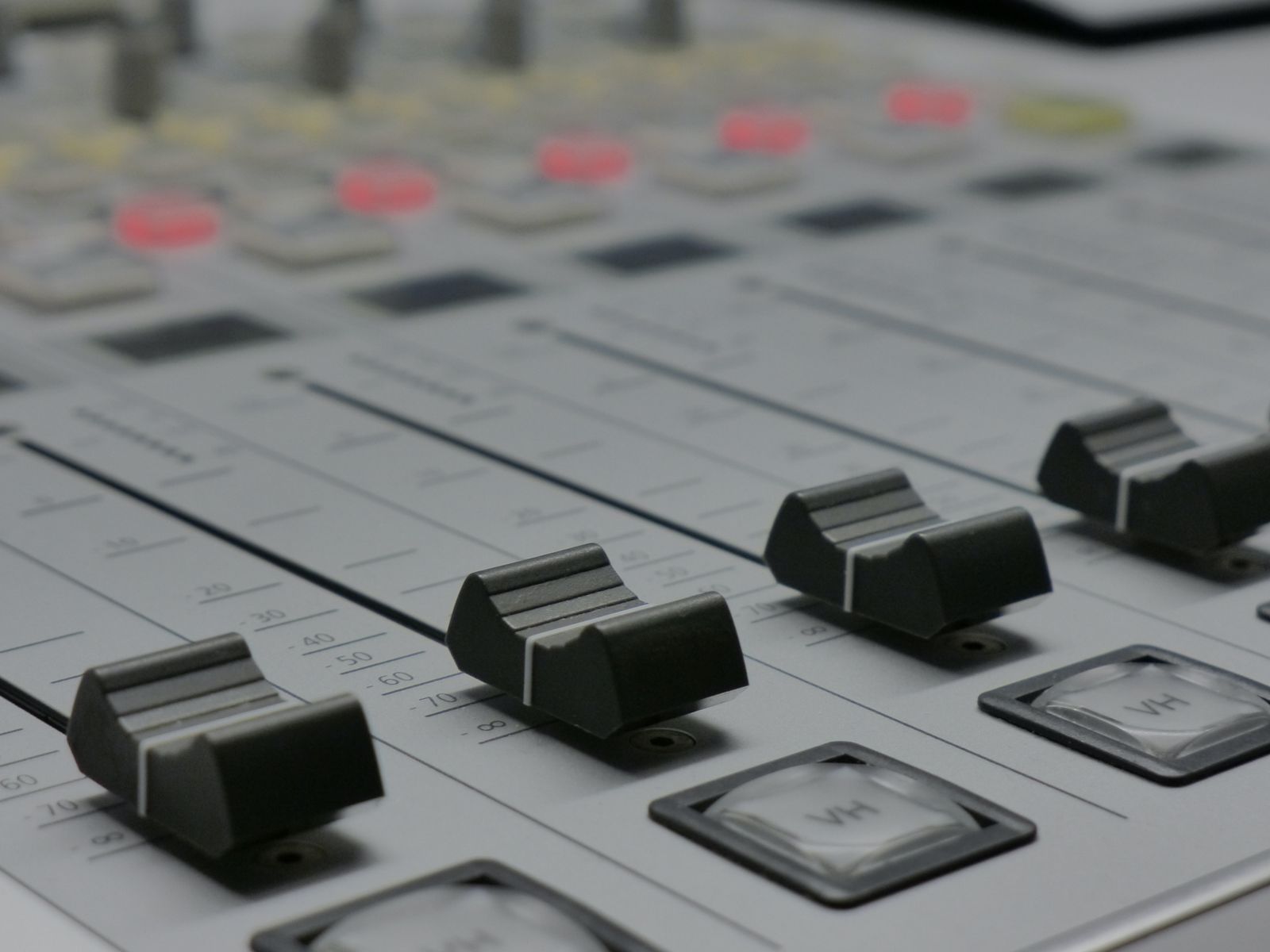 Close-up of the faders of a pale grey mixing console