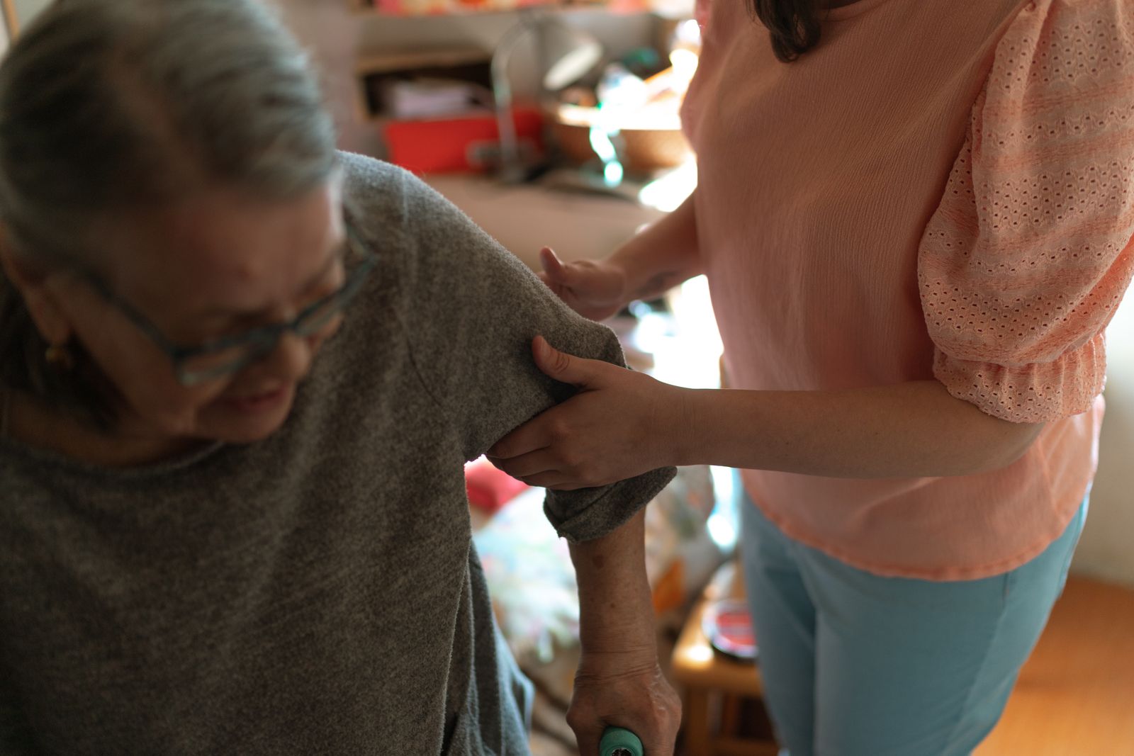 A care worker supporting an older woman as she walks at home