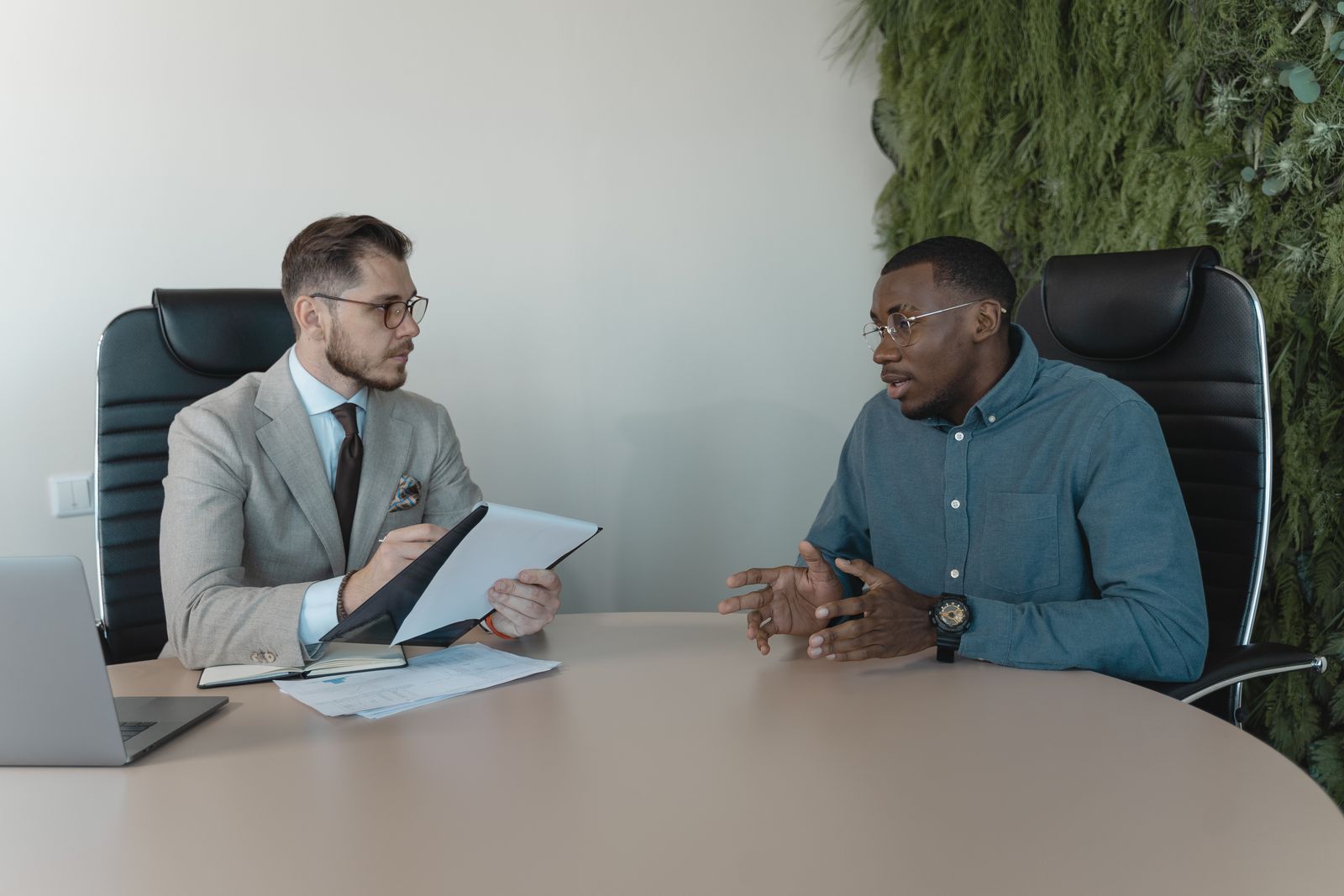 Two men in a job interview at a meeting table in a bright office