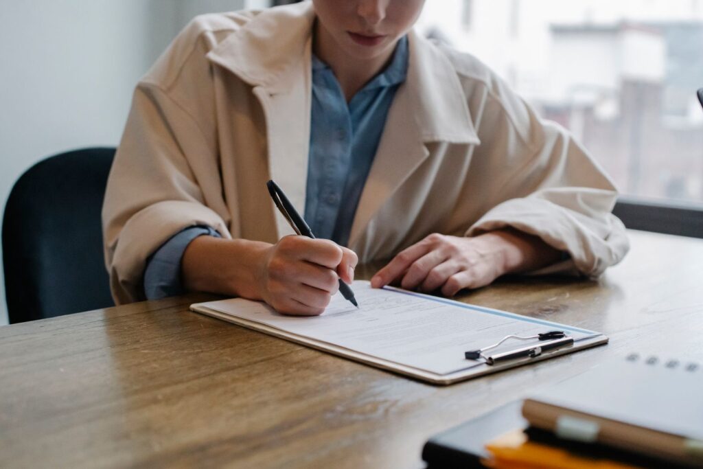 A job seeker filling in a form on a clipboard at a table