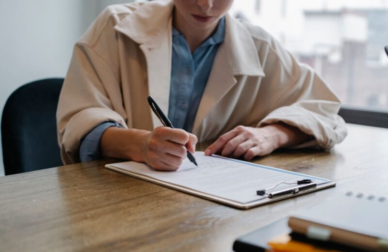 A job seeker filling in a form on a clipboard at a table