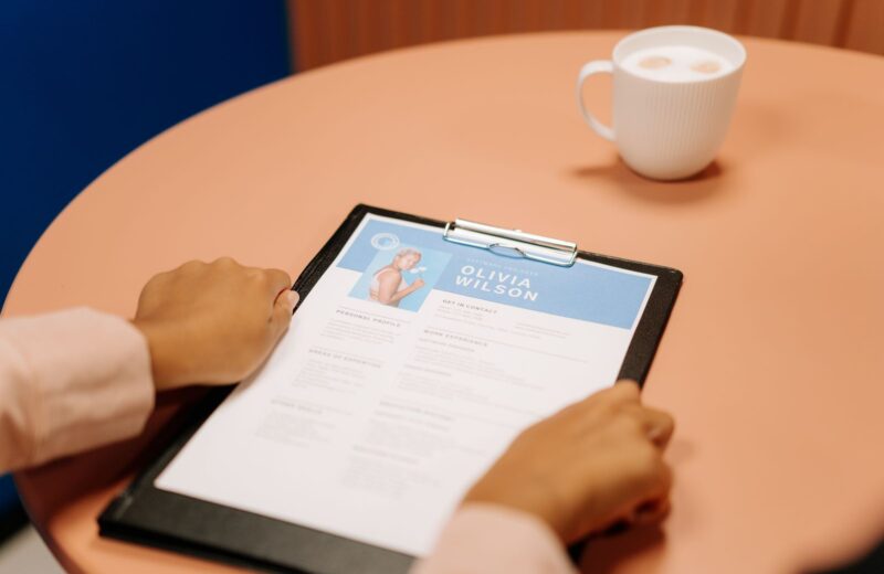 Hands holding a CV on a clipboard during an interview