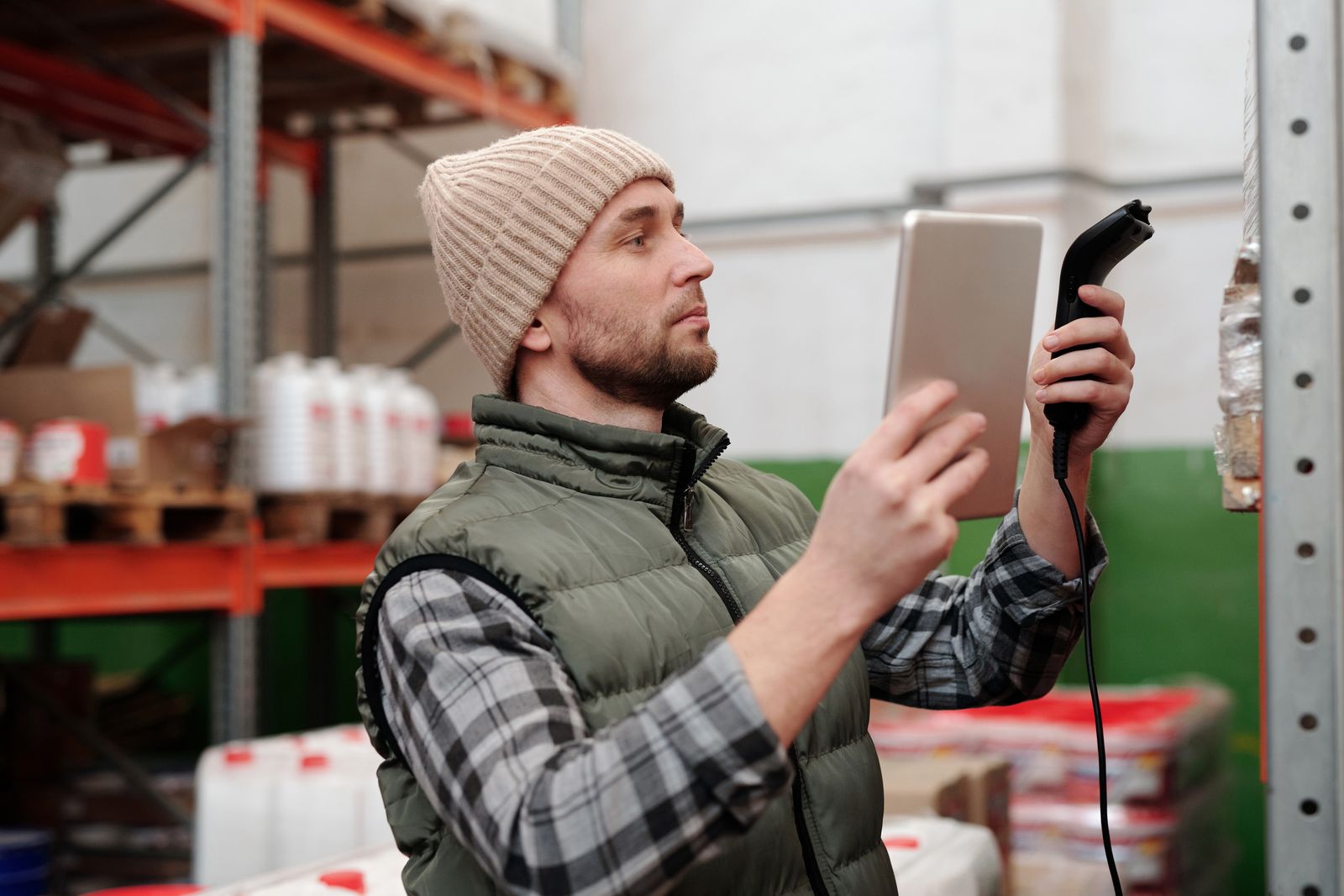 A warehouse worker checking stock with a handheld scanner and a tablet
