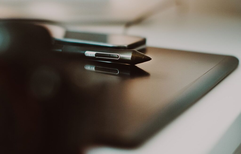 A stylus resting on a dark drawing tablet, close up