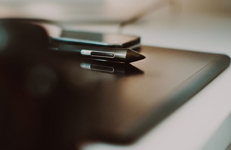 A stylus resting on a dark drawing tablet, close up