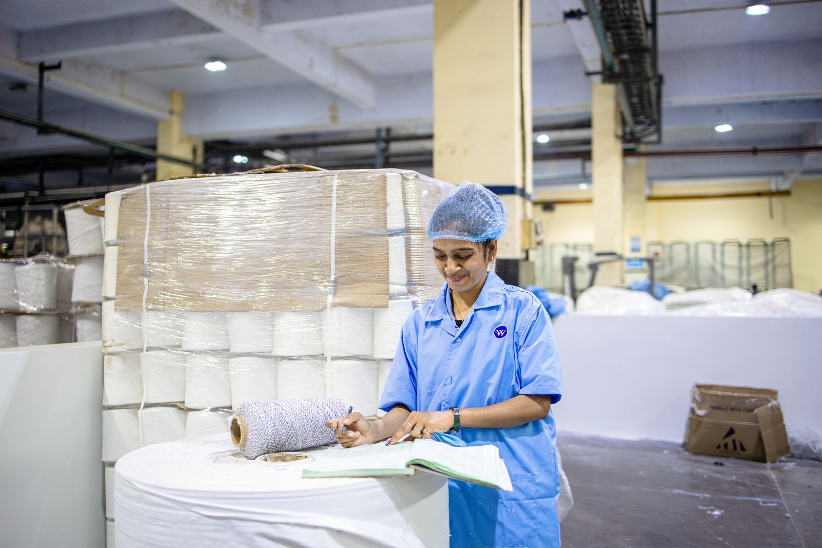 A worker checking paperwork at a table on a factory floor