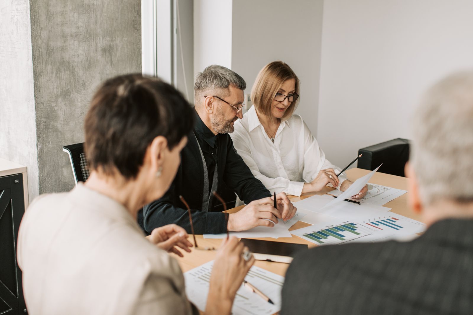 Four people working through papers around a meeting table
