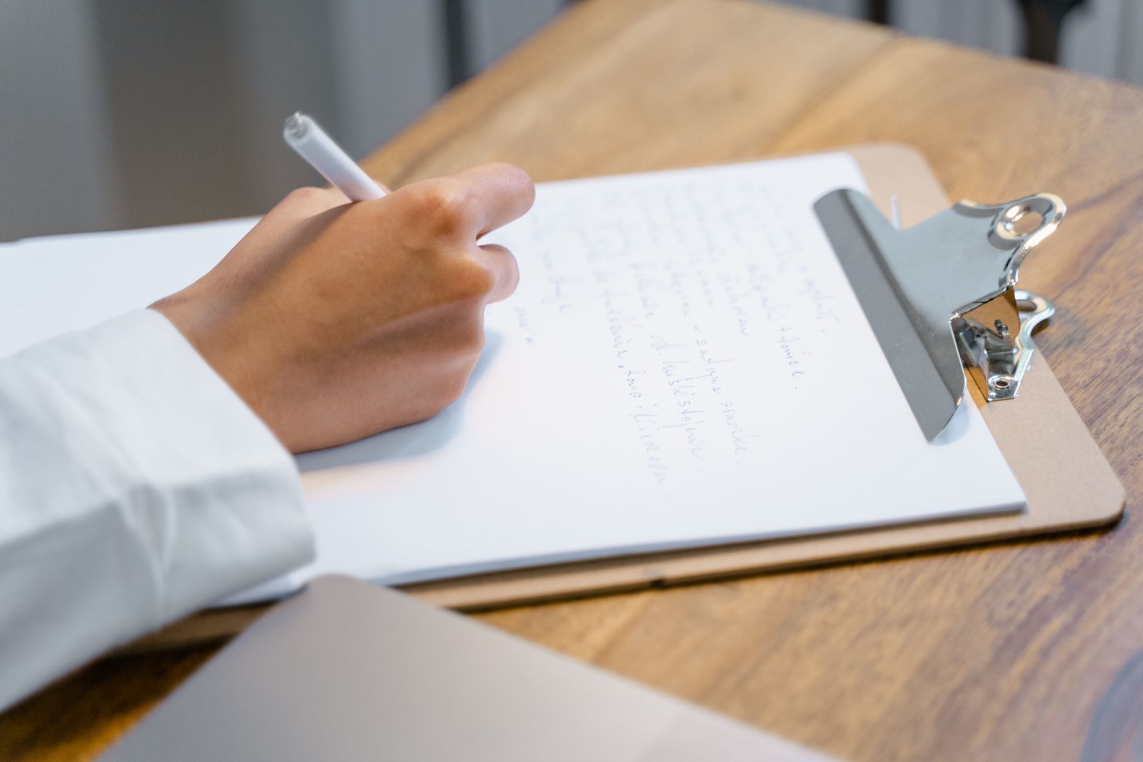 A hand writing on a clipboard list at a table