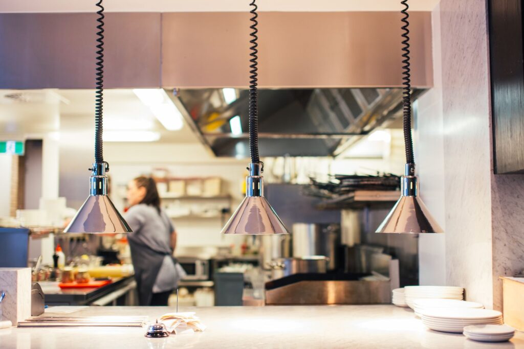 A cook working at the pass under heat lamps